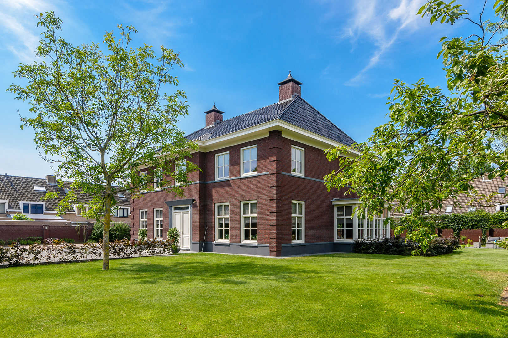 Vrijstaande bakstenen villa met een groene tuin en volwassen bomen