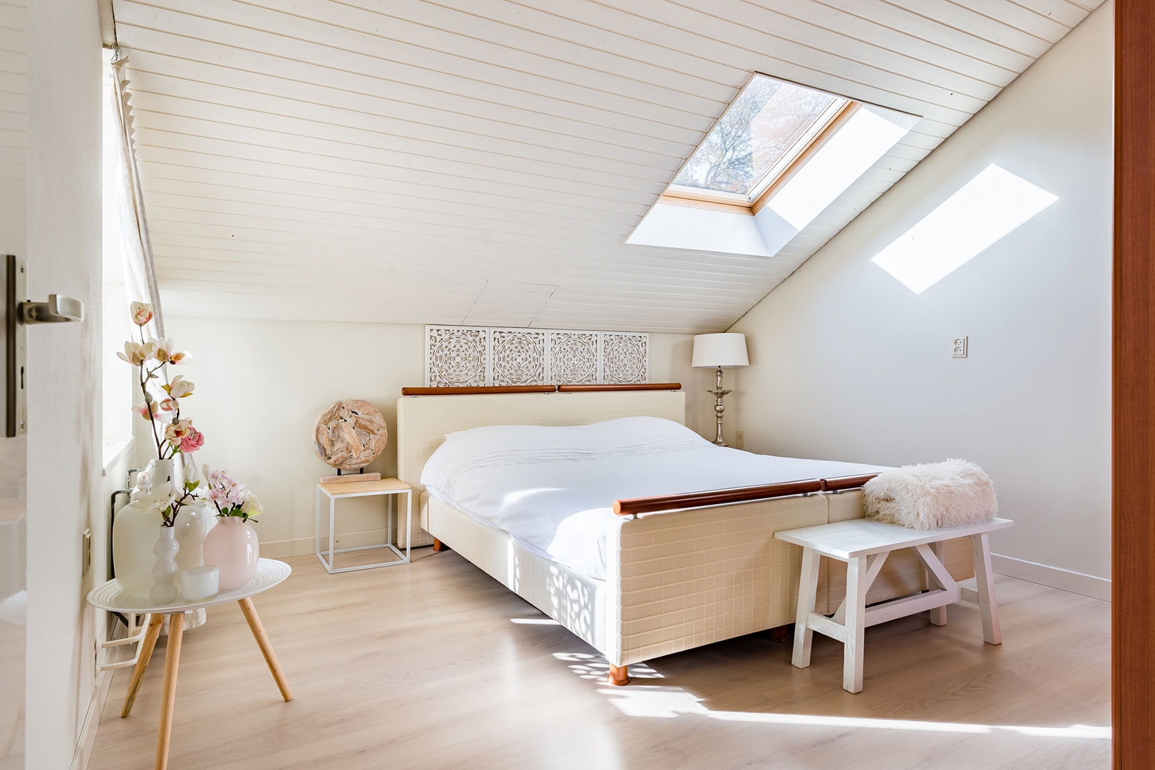Zonnige slaapkamer onder een schuin dak met dakraam